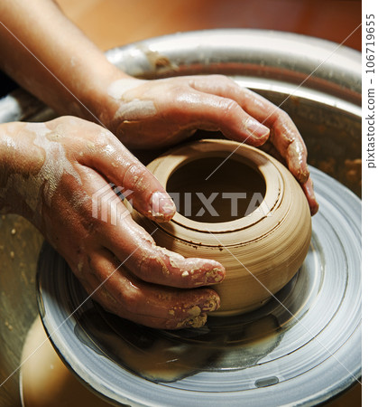Master's hands mold a jug on a potter's wheel Master's hands mold a jug on a potter's wheel 106719655
