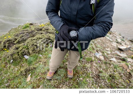 Successful woman hiker  set the sports watch at mountain top in tibet 106720533
