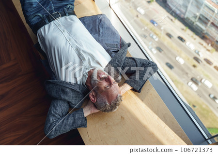 Top view of tired senior businessman resting on wooden banch in office during break time Top view of tired senior businessman resting on wooden banch in office during break time 106721373