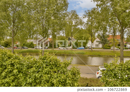 some trees and water in the middle of a small town, with cars parked on either side of the river 106722869