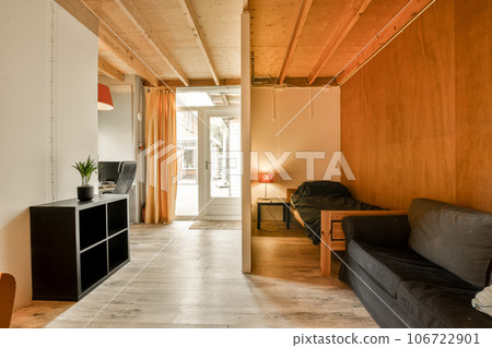 a living room with wood paneled walls and black couch in the center of the room, there is a tv on the wall a living room with wood paneled walls and black couch in the center of the room, there is a tv on the wall 106722901