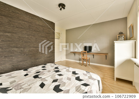 a bedroom with a bed, desk and television on the wall in front of the bed is made out of wood 106722909