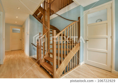 a wooden staircase way in a house with light blue walls and white trim around the banomulan railing 106722929