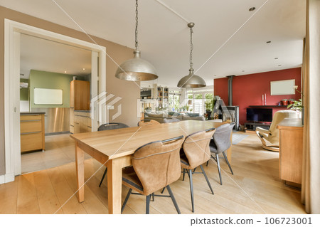 a dining room with wood flooring and red accent wall in the kitchen, living room is visible on the right side a dining room with wood flooring and red accent wall in the kitchen, living room is visible on the right side 106723001