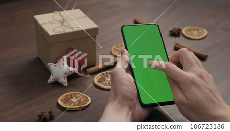 man hand use smartphone with green screen with christmas gifts and decorations on background man hand use smartphone with green screen with christmas gifts and decorations on background 106723186