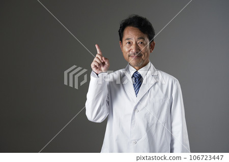 Middle-aged doctor pointing to the left, black background Middle-aged doctor pointing to the left, black background 106723447
