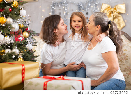 Portrait of grandmother, mother and girl at Christmas on sofa bonding, loving and enjoying holiday season 106723992