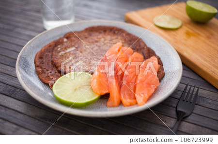 Salted salmon fillet with buckwheat pancakes and lime Salted salmon fillet with buckwheat pancakes and lime 106723999