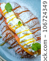 Sweet croissant sandwich dessert filled with whipped cream mixed with custard on blue plate  106724349