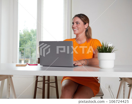 smiling woman working at home with laptop 106724425