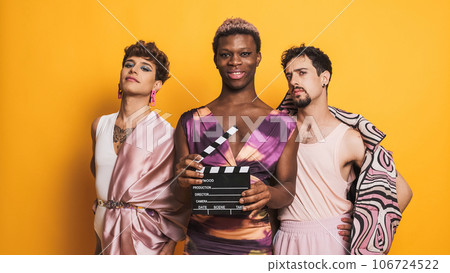 Three transgender male models posing with a film clapperboard 106724522