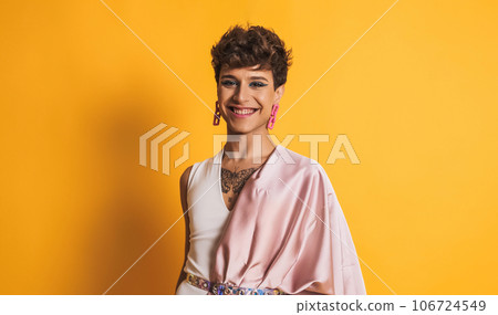 Transgender man with pink clothes and make up smiling at the camera on yellow Transgender man with pink clothes and make up smiling at the camera on yellow 106724549