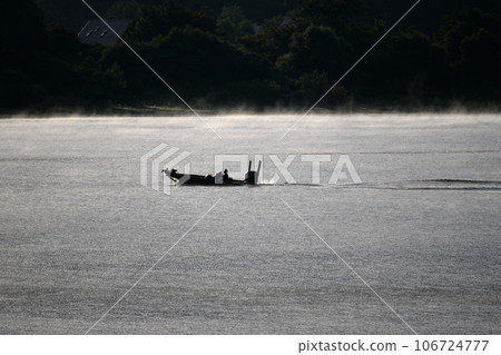 Lake in the morning mist, sparkling water surface 106724777