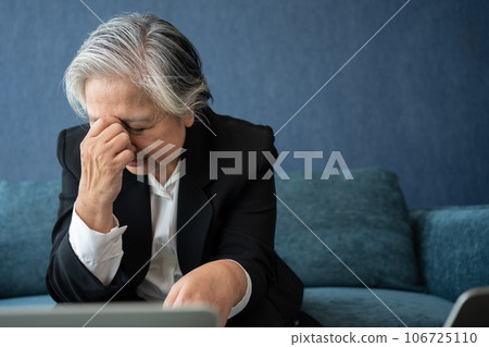 Overworked tired old lady holding head feeling headache. Asian senior business woman stress from hard work. Frustrated business woman thinks seated at workplace, feel distressed looks helpless concept Overworked tired old lady holding head feeling headache. Asian senior business woman stress from hard work. Frustrated business woman thinks seated at workplace, feel distressed looks helpless concept 106725110