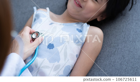 Asian woman pediatrician doctor hold stethoscope for exam a little girl patient and heck heart lungs of kid, Good family doctor visiting child at home, Healthcare and medicine for childhood concept. Asian woman pediatrician doctor hold stethoscope for exam a little girl patient and heck heart lungs of kid, Good family doctor visiting child at home, Healthcare and medicine for childhood concept. 106725611