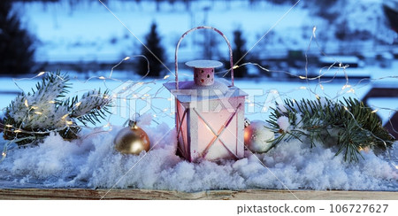 Christmas lantern and New Year decorations on the snow, illumination and snowdrifts in the background, evening, winter 106727627