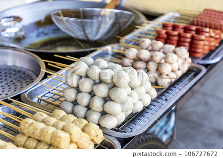 Thai style meatballs on skewers It will come in a cart to be sold on the public side of the road. There is a pan and hot oil for frying. The dipping sauces are both sweet and spicy. Selective focus. 106727672
