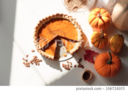 Festive homemade appetizing ripe pumpkin pie, pumpkin tart decorated with nuts, minimalistic light background 106728055