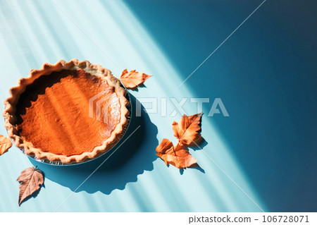 Festive homemade appetizing ripe pumpkin pie, pumpkin tart decorated with nuts, minimalistic blue background with hard shadows, top view. Traditional seasonal fall baking, Thanksgiving Festive homemade appetizing ripe pumpkin pie, pumpkin tart decorated with nuts, minimalistic blue background with hard shadows, top view. Traditional seasonal fall baking, Thanksgiving 106728071