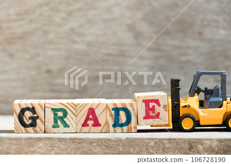 Toy forklift hold letter block  in word grade on wood background 106728190