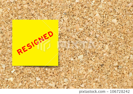 Yellow note paper with word resigned on cork board background with copy space 106728242