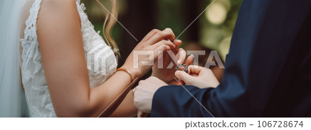 Wedding hands of the bride and groom ceremonially put wedding rings on their fingers. AI generated. 106728674