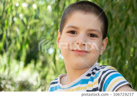 Portrait of a handsome six-year-old boy in a striped t-shirt in nature, a place for text to copy space Portrait of a handsome six-year-old boy in a striped t-shirt in nature, a place for text to copy space 106729257