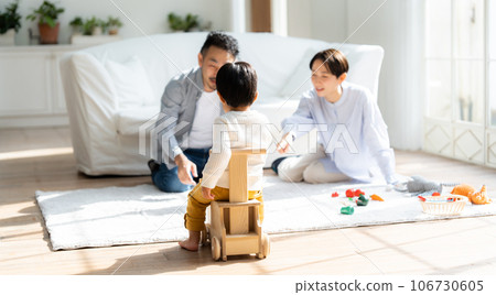 Family of three playing in the living room 106730605