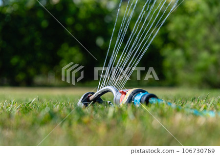 Automatic sprinkler system watering the lawn on a background of green grass. Automatic sprinkler system watering the lawn on a background of green grass. 106730769