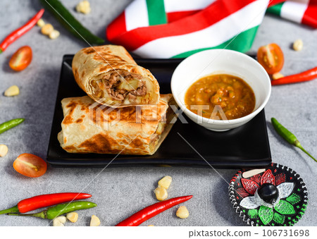 Mexican burrito with beef, french fries and cheese served with sauce borracha 106731698