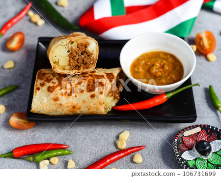 Mexican burrito with chorizo, potato and cheese served with sauce barracha Mexican burrito with chorizo, potato and cheese served with sauce barracha 106731699