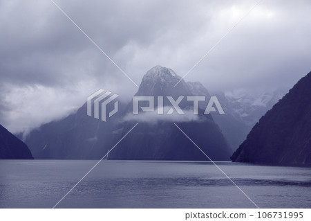 Photograph of mountains in clouds and mist in Milford Sound on the South Island of New Zealand Photograph of mountains in clouds and mist in Milford Sound on the South Island of New Zealand 106731995