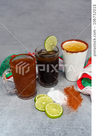 Mexican drinks Charro Negro, Jarrito, Cerveza roja on a gray table with salt pepper and lime Mexican drinks Charro Negro, Jarrito, Cerveza roja on a gray table with salt pepper and lime 106732018