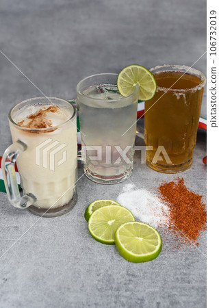 Mexican drinks Horchata water, Lime juice and beer on a gray table with salt pepper and lime Mexican drinks Horchata water, Lime juice and beer on a gray table with salt pepper and lime 106732019