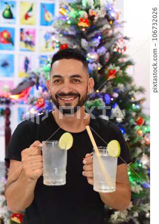 Mexican man holding mexican drinks Horchata water and lemon juice against christmas tree Mexican man holding mexican drinks Horchata water and lemon juice against christmas tree 106732026