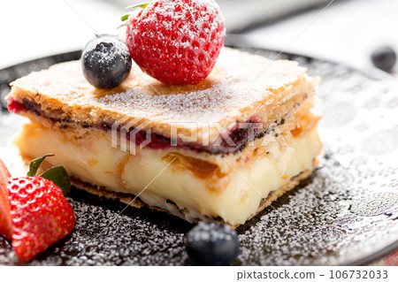 A piece of Napoleon cake with poppy seeds and cherries 106732033