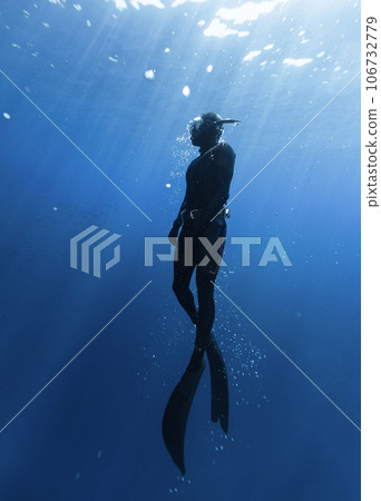 Freediver Swimming in Deep Sea With Sunrays. 106732779