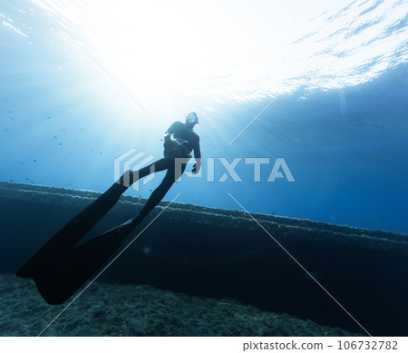 Freediver Swimming in Deep Sea and Exploring Ship Wreck. Freediver Swimming in Deep Sea and Exploring Ship Wreck. 106732782