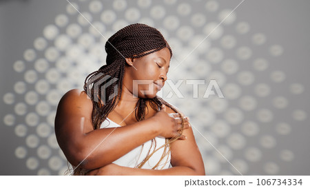 Female model advertising face cream and skincare routine in studio, using moisturizer and natural cosmetics on camera. Radiant luminous woman with glowing look promoting beauty products. Female model advertising face cream and skincare routine in studio, using moisturizer and natural cosmetics on camera. Radiant luminous woman with glowing look promoting beauty products. 106734334