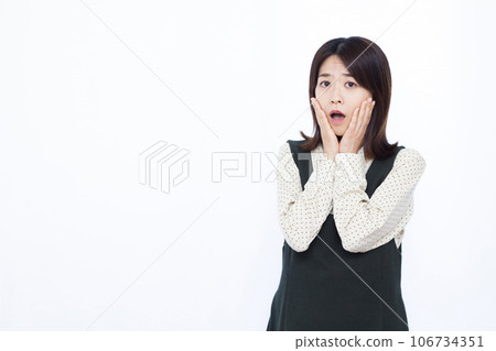 A woman in her thirties who is surprised in front of a white background 106734351