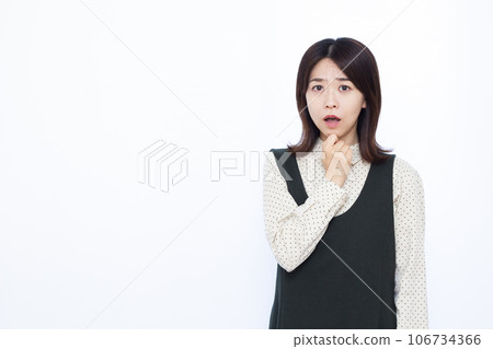 A woman in her thirties who is surprised in front of a white background 106734366