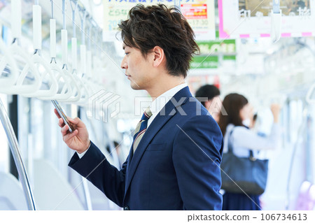 A man in a suit riding a train Photo cooperation "Keio Electric Railway Co., Ltd." A man in a suit riding a train Photo cooperation "Keio Electric Railway Co., Ltd." 106734613