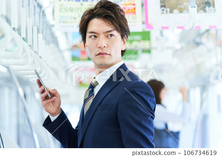 A man in a suit riding a train Photo cooperation "Keio Electric Railway Co., Ltd." A man in a suit riding a train Photo cooperation "Keio Electric Railway Co., Ltd." 106734619