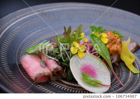 Japanese black beef roast beef decorated with edible flowers and herbs. 106734987