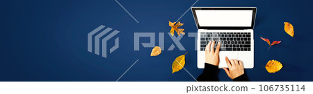 Autumn leaves with person using a laptop computer Autumn leaves with person using a laptop computer 106735114