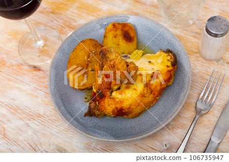 Pieces of fried chicken served with baked potato slices 106735947