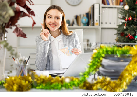 Portrait of happy female manager with money in an envelope - christmas present Portrait of happy female manager with money in an envelope - christmas present 106736013