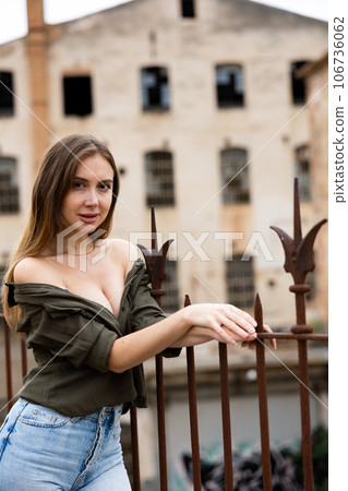 Woman standing near fence against abandoned building Woman standing near fence against abandoned building 106736062