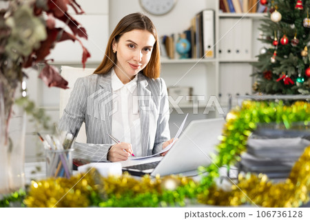 Portrait of young woman office worker in Christmas decorated office 106736128