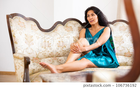 Portrait of woman in nightgown sitting on sofa at home Portrait of woman in nightgown sitting on sofa at home 106736192